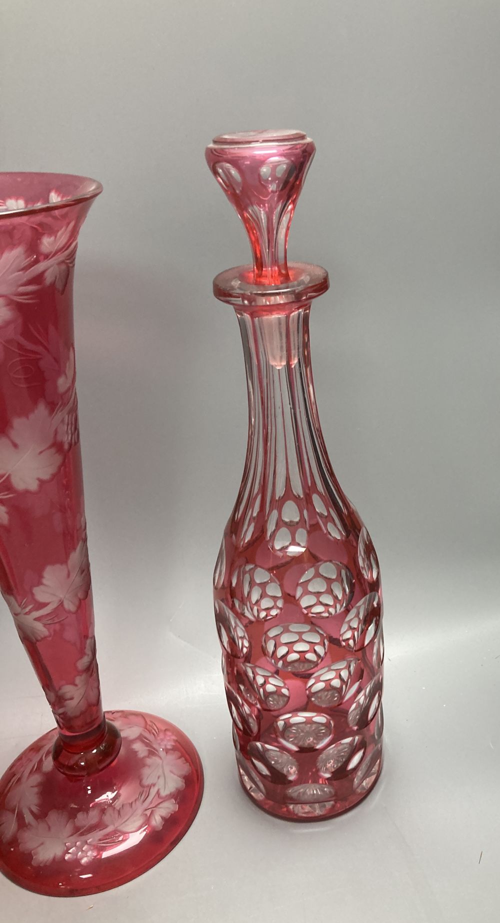 A collection of nine pieces of cranberry and ruby coloured glass, including a pair of decanters, two vases and a carafe and tumbler